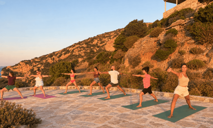 Outdoor yoga class in warrior pose on a hillside terrace